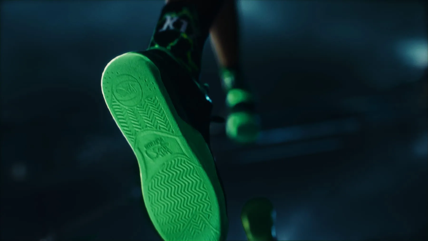The sole of a K1X shoe, green tread against the night city