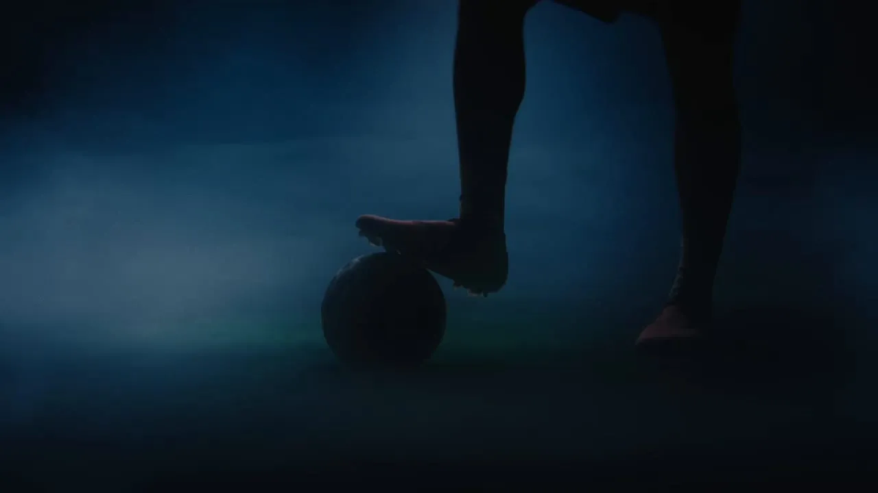 A boot resting on the ball in low blue mist