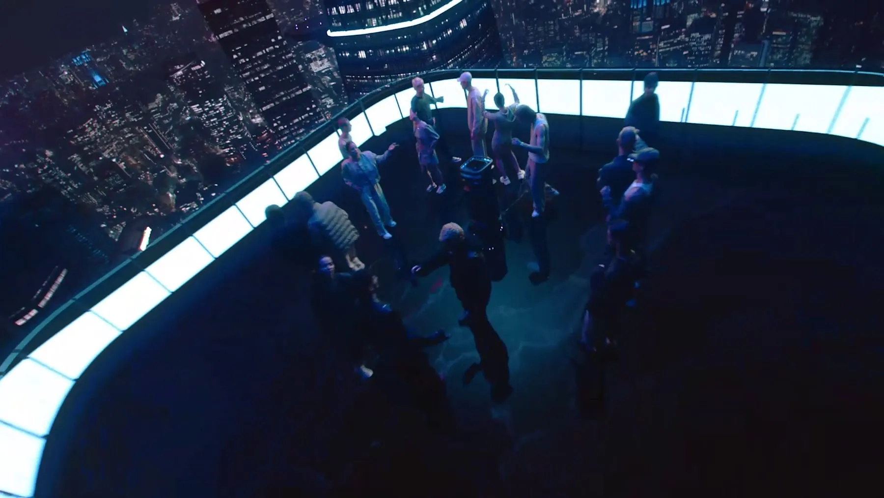 A rooftop crowd at night, the city lit behind the glass