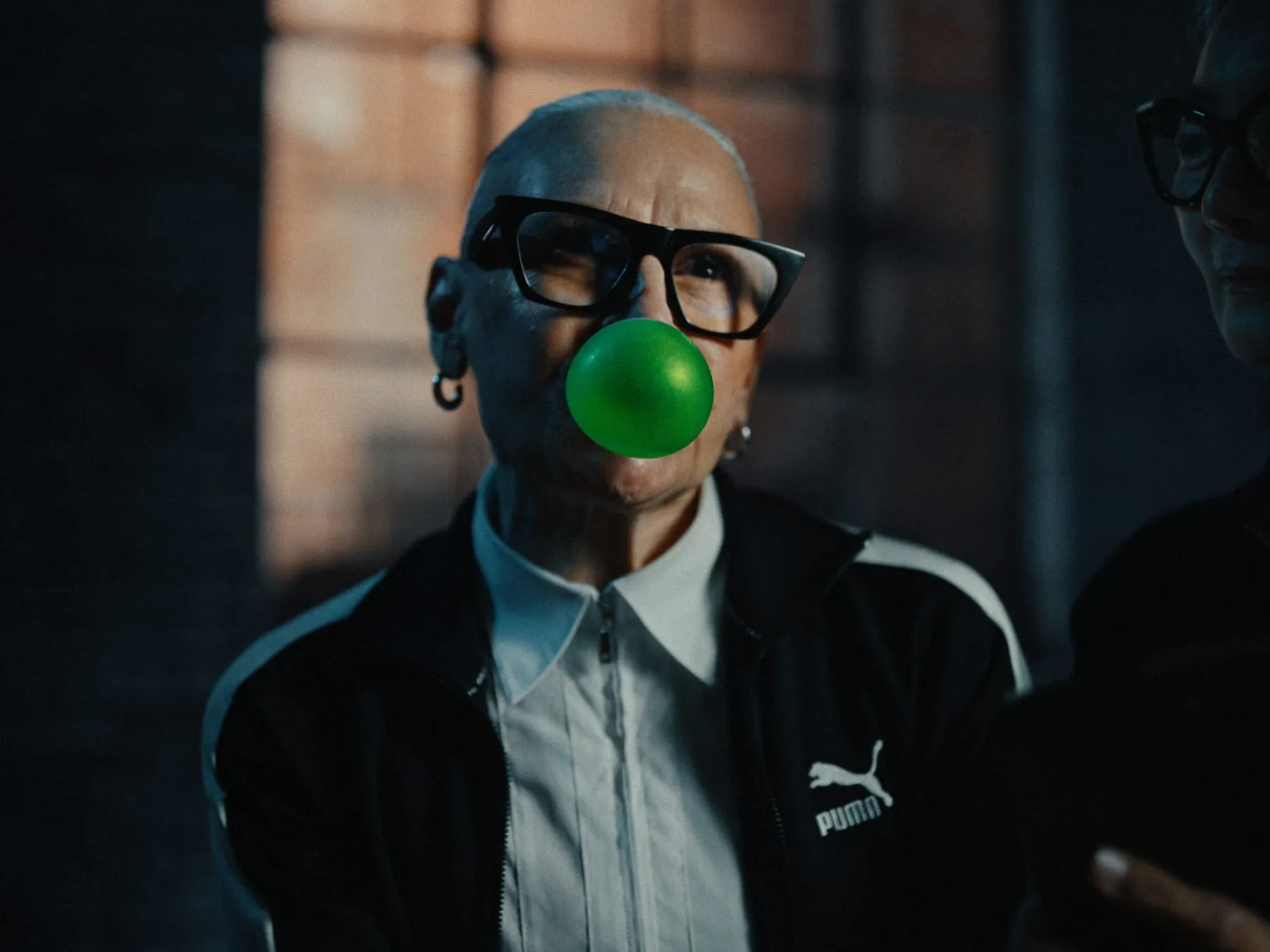 A$AP Rocky in a PUMA jacket and glasses, green bubblegum held mid-blow