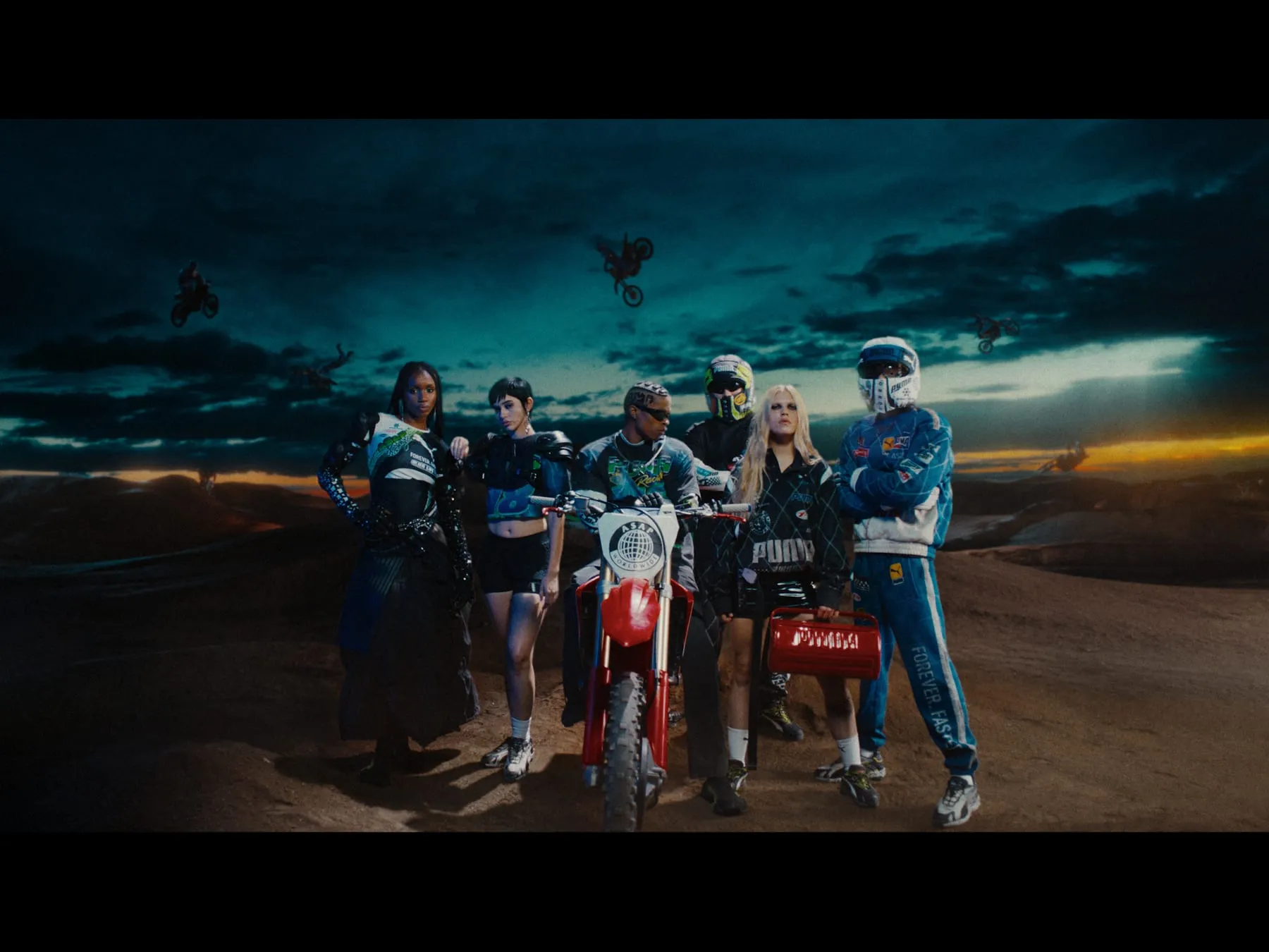 The full cast and their bikes lined up against an evening sky