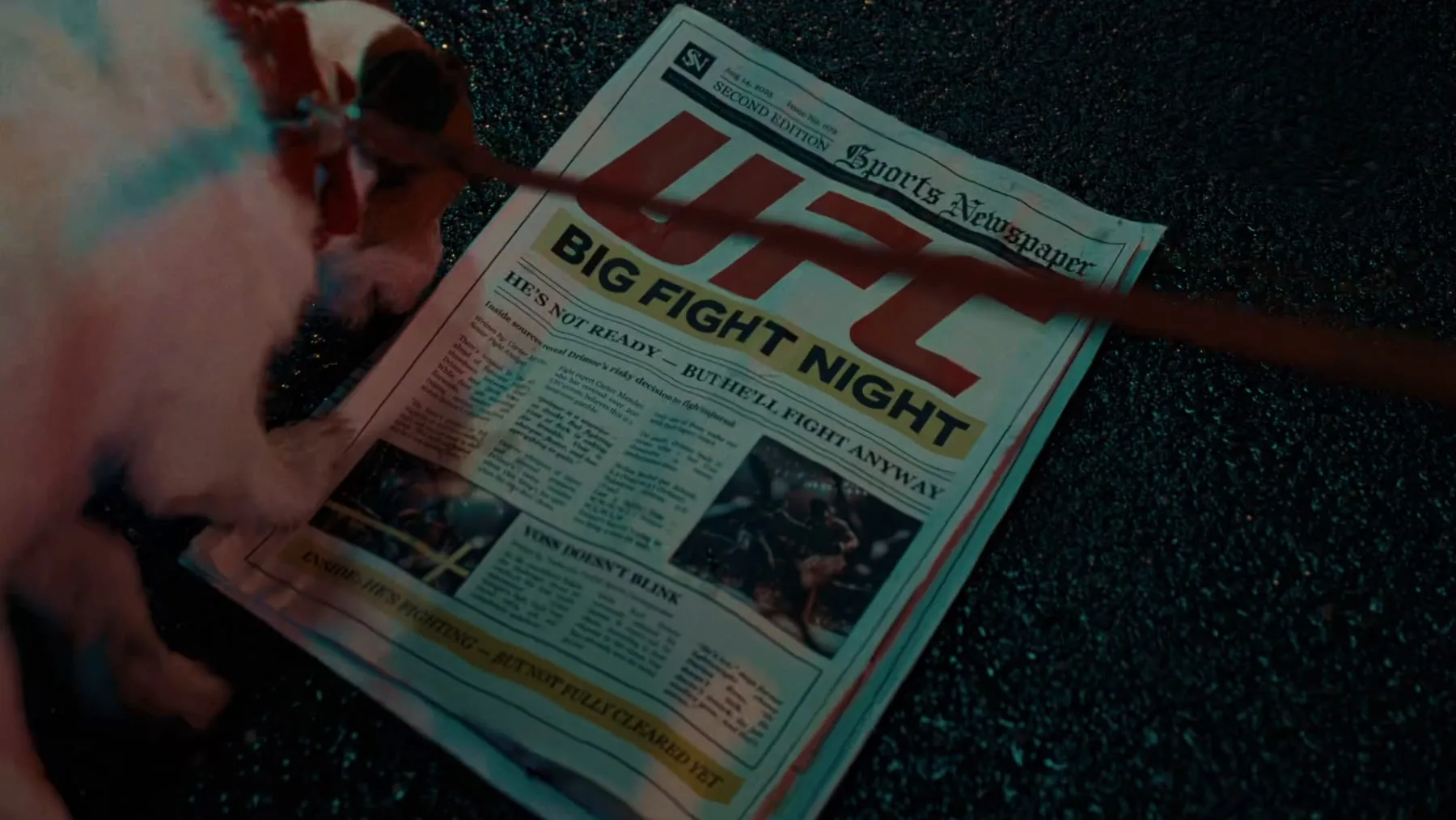 A UFC fight-night newspaper lying on wet asphalt